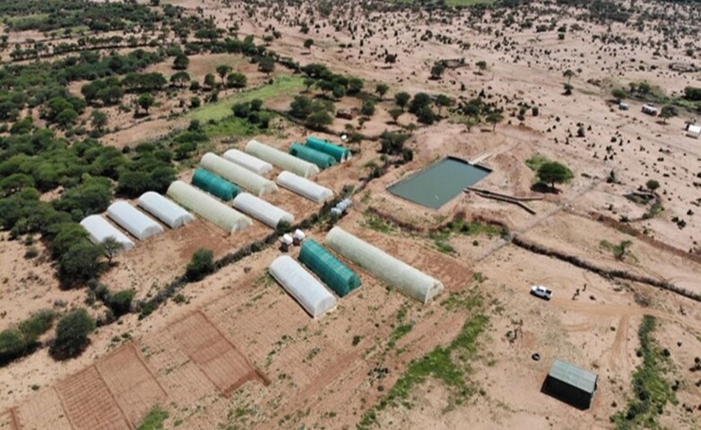 Aerial view of smart greenhouses and a water reservoir in a semi-arid landscape, part of a water innovation centre in Somalia.