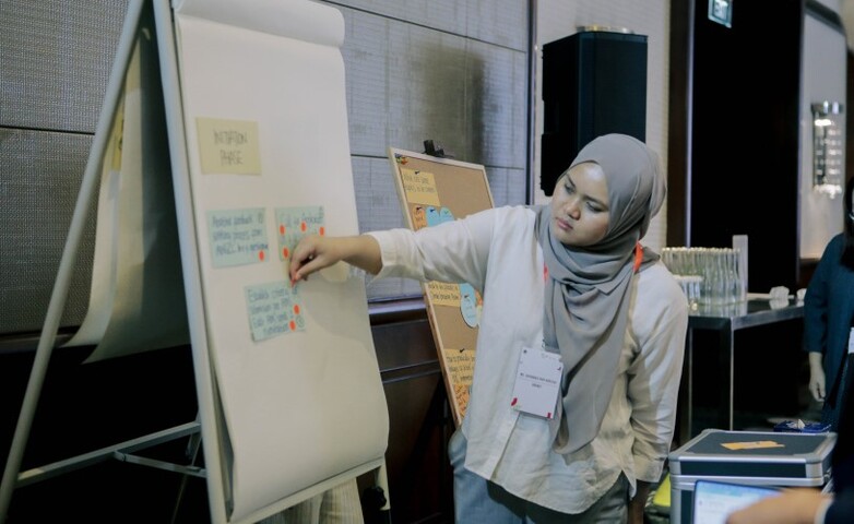 A workshop participant puts a sticker on a card to discuss a topic on innovative climate action.