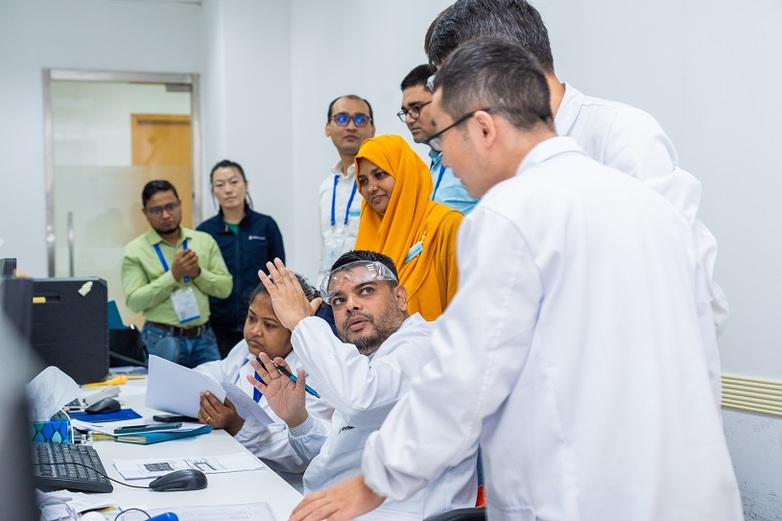 Experts talking while sitting and standing around a computer.