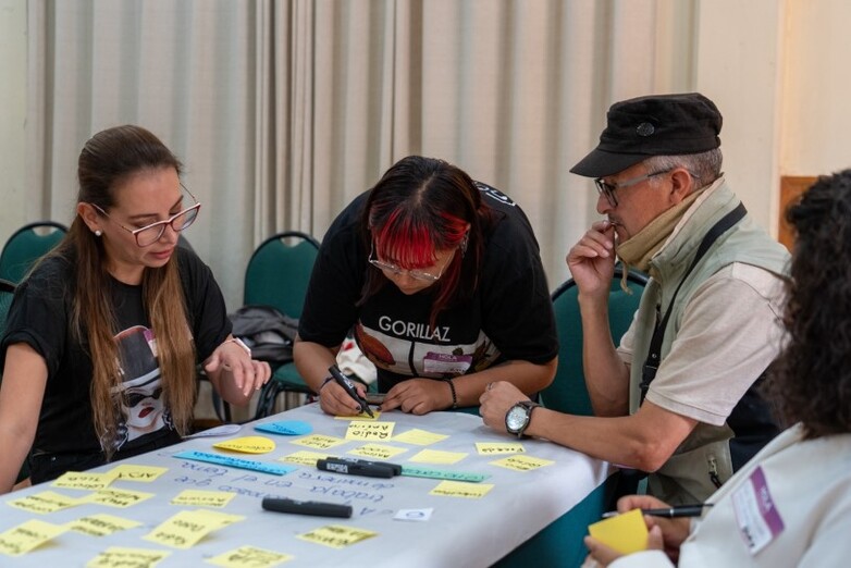 Person writing keywords on sticky notes while three others are watching.