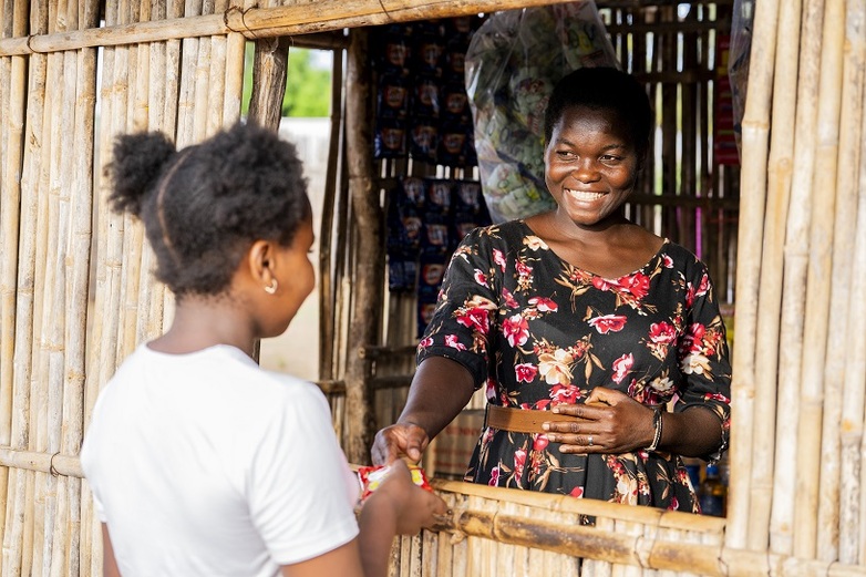 A woman selling products from her stall to a customer.