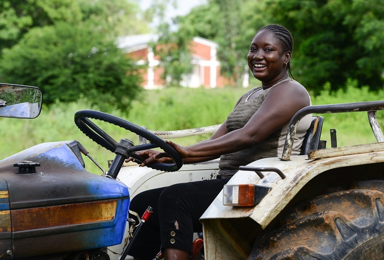 A woman steering a tractor laughing.