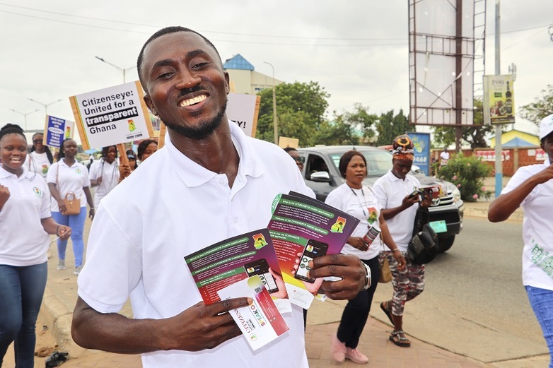 A man holding flyers for the CitizensEye app during a rally.