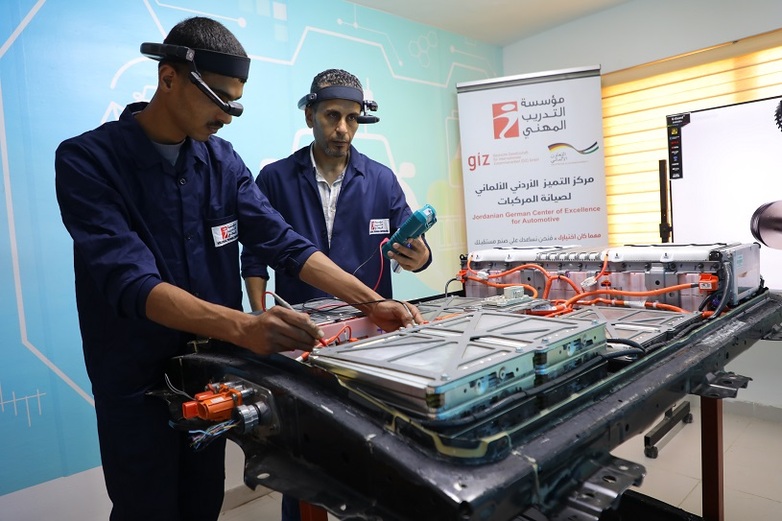 Two men use Augmented Reality in a training programme for hybrid and electric vehicles at the Automotive Center of Excellence.