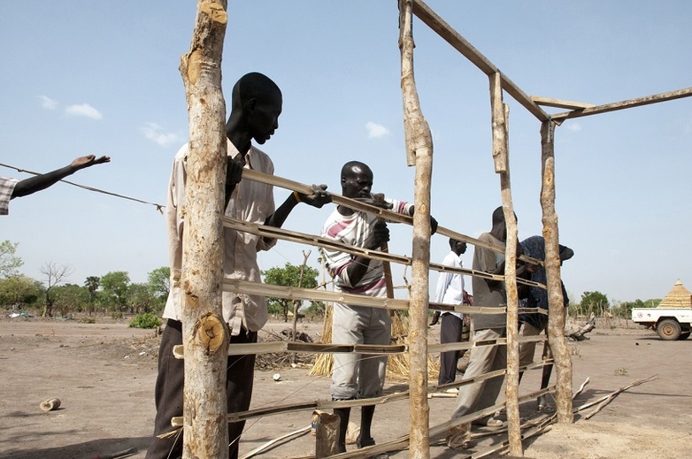 Refugees and local people working together to build a shelter. 