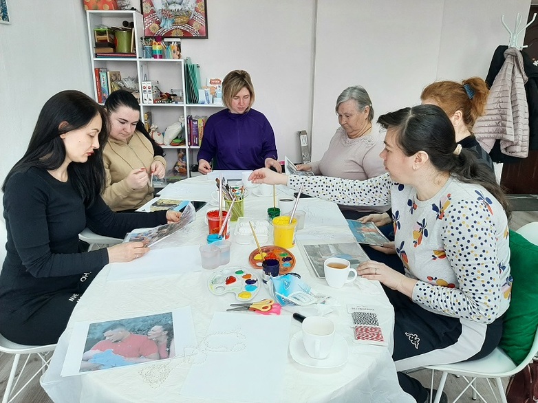 Six women sitting around a table painting