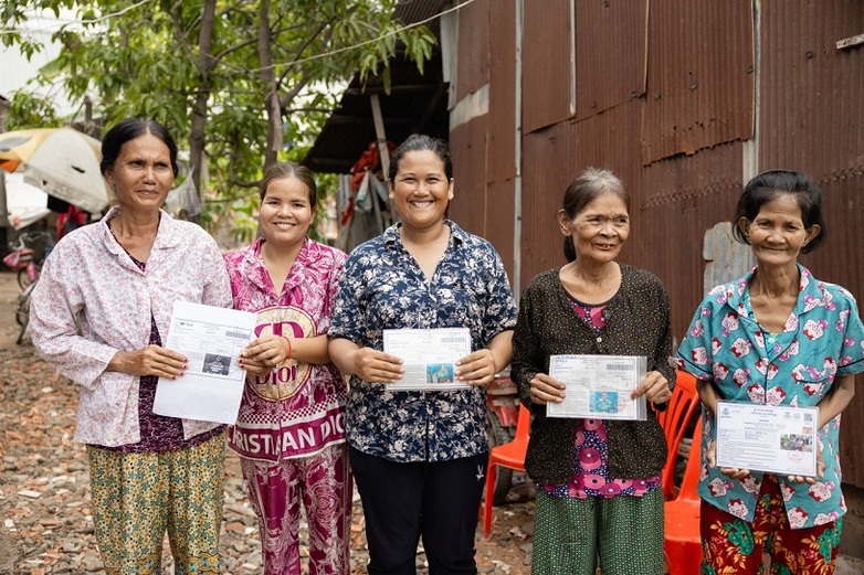 Five women living in poverty are holding up to the camera laminated equity cards featuring their personal details; the cards give them access to social assistance benefits and basic health care.