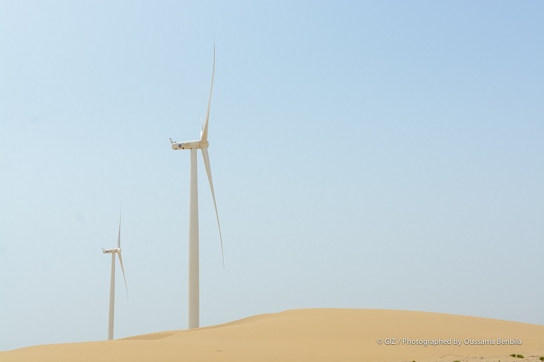 Two wind turbines in a desert.