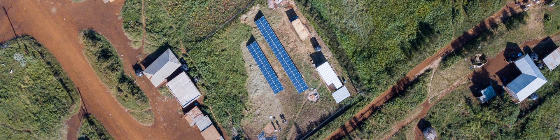 A drone image shows a solar installation among scattered buildings in a rural area.