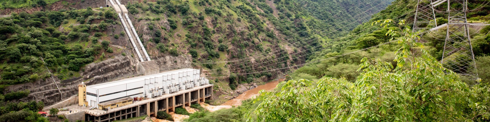 A hydropower plant in a hilly green landscape.