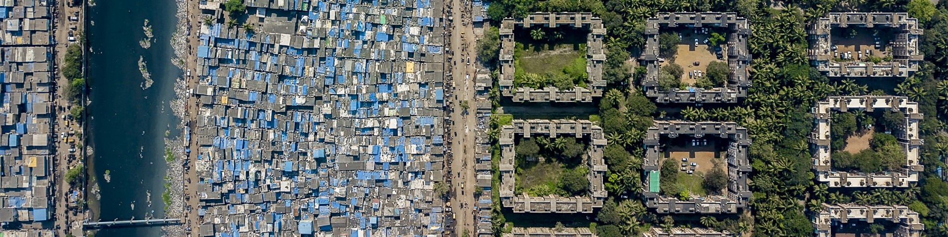 A densely built-up slum next to a neighbourhood with green, large residential buildings 