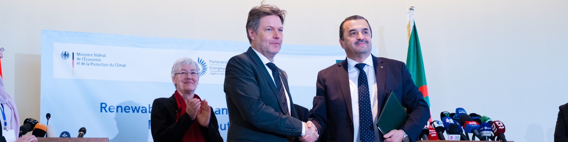 Robert Habeck and Mohamed Arkab shaking hands on a stage.