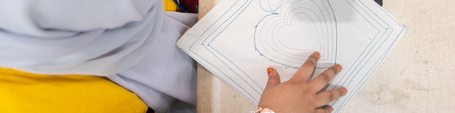 A woman is practicing to stich a heart with a sewing machine.