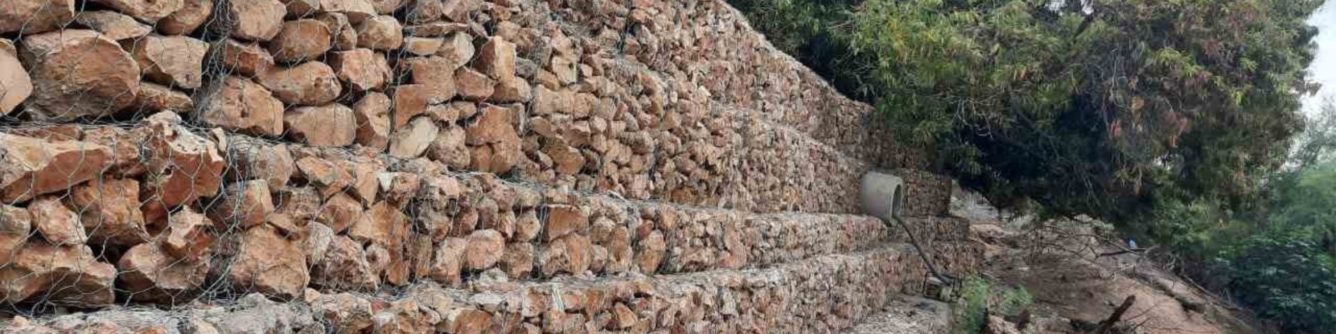 Stone terraces reinforced with wire mesh to prevent soil erosion and manage water flow in a rural area of Somalia.