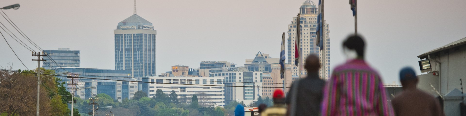 Many people walk on the pavement next to a road in Johannesburg, South Africa.