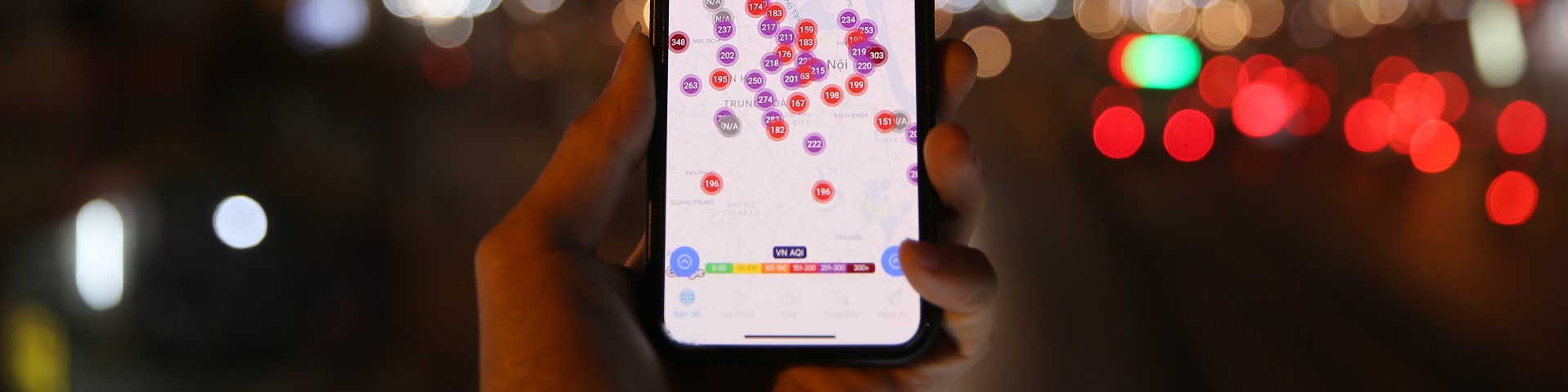 A hand holding a smartphone, which shows places marked on an app.