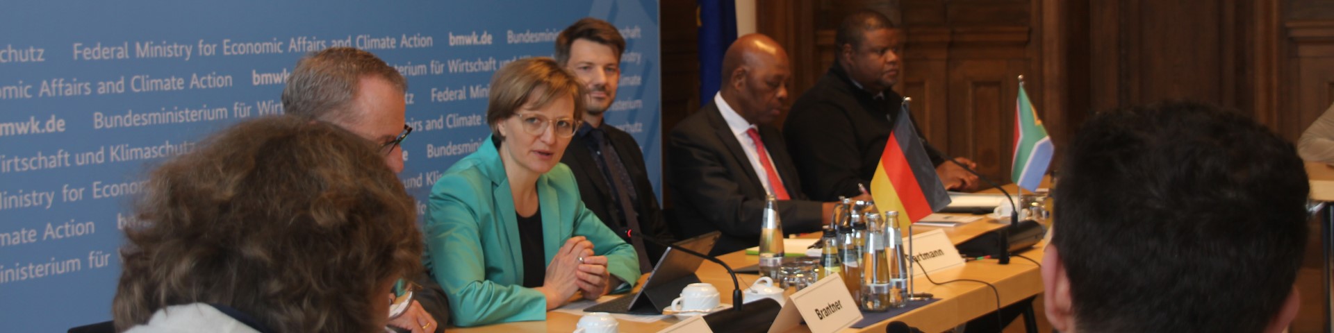 Representatives of Germany and South Africa sit at a long table with national flags on it at a meeting of the South African-German Hydrogen Task Force.