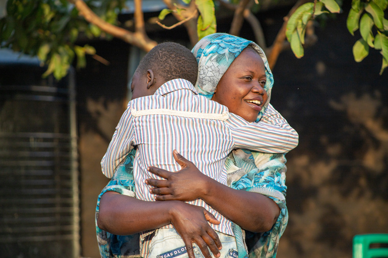 A smiling woman holds a small child. 