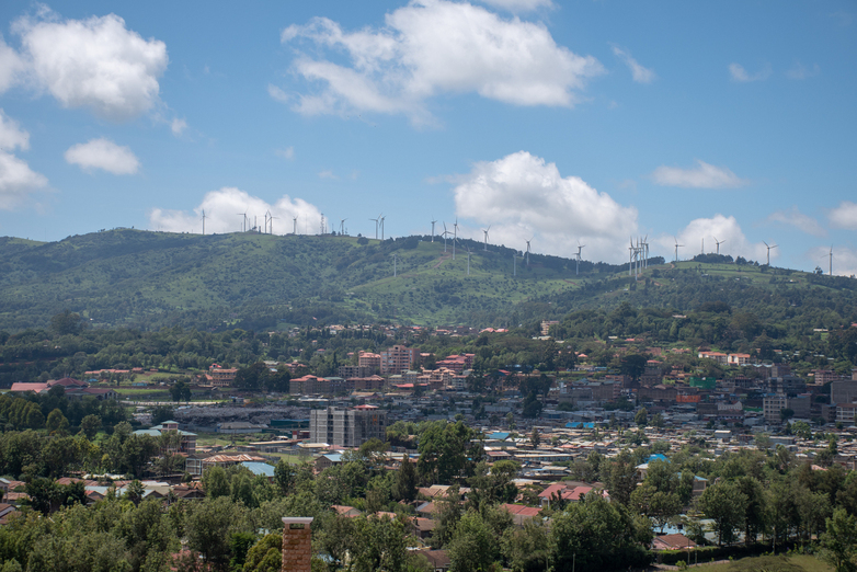 A town with wind turbines on a hill.