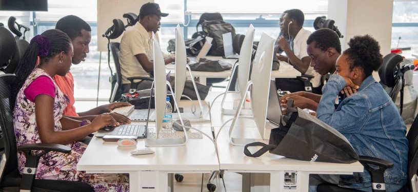 Seven focused young people sitting at their computers in an Orange Digital Center.