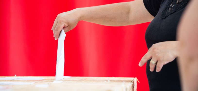 A woman deposits a ballot paper in a ballot box.