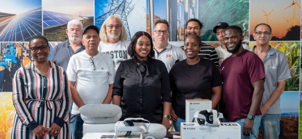 A diverse group of people posing together in front of a table displaying Oculus VR goggles.