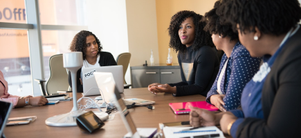 A group of women sitting around a table, working together.