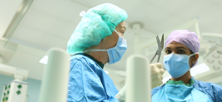 A woman explains tools to a specialist in the operating theatre.