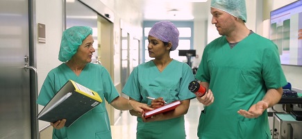 Three doctors are having a conversation in a hospital corridor.