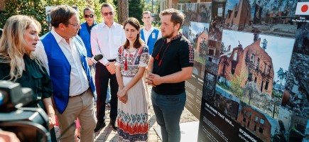 A group of people stand around a poster and have a lively discussion about the information presented.