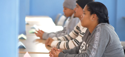 Trainees sit at school desks.