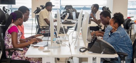 Seven focused young people sitting at their computers in an Orange Digital Center.