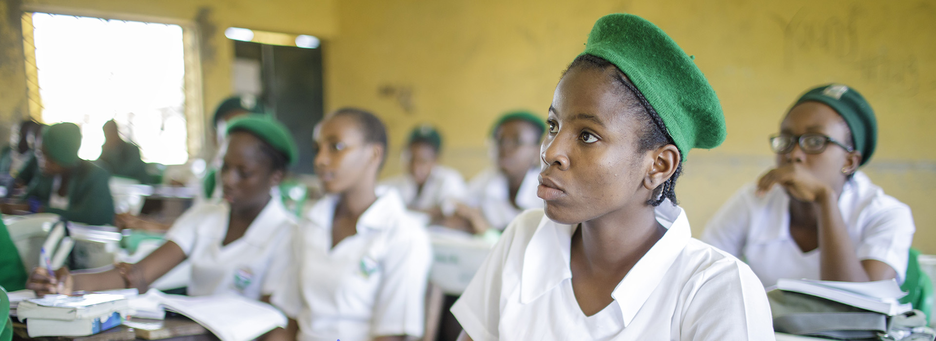 Young women in uniform sit in a school class.