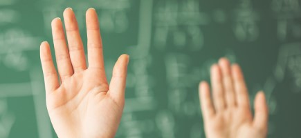 Hands raised in a message in front of a blackboard