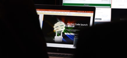 Laptop screen showing a slide with the event title ' Market Code Launch '.